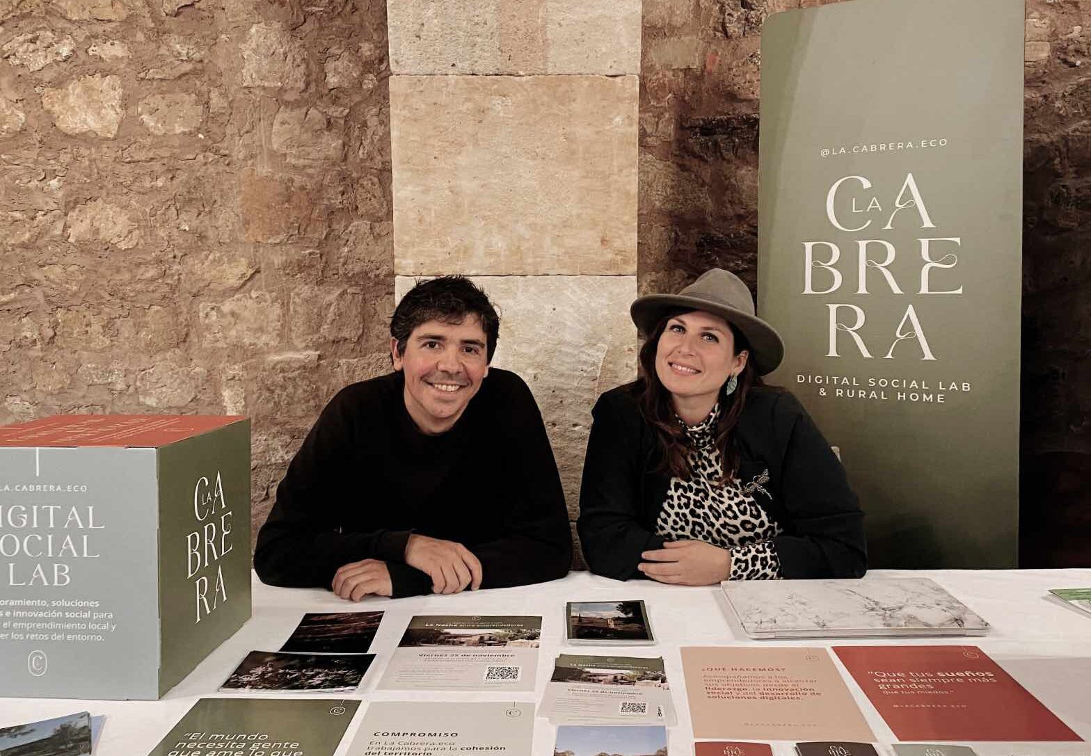 Imagen de dos personas en un stand mirando a cámara y sonriendo. Presentando La Cabrera.eco. Las Sesiones Brújula te ayudarán a ganar claridad.